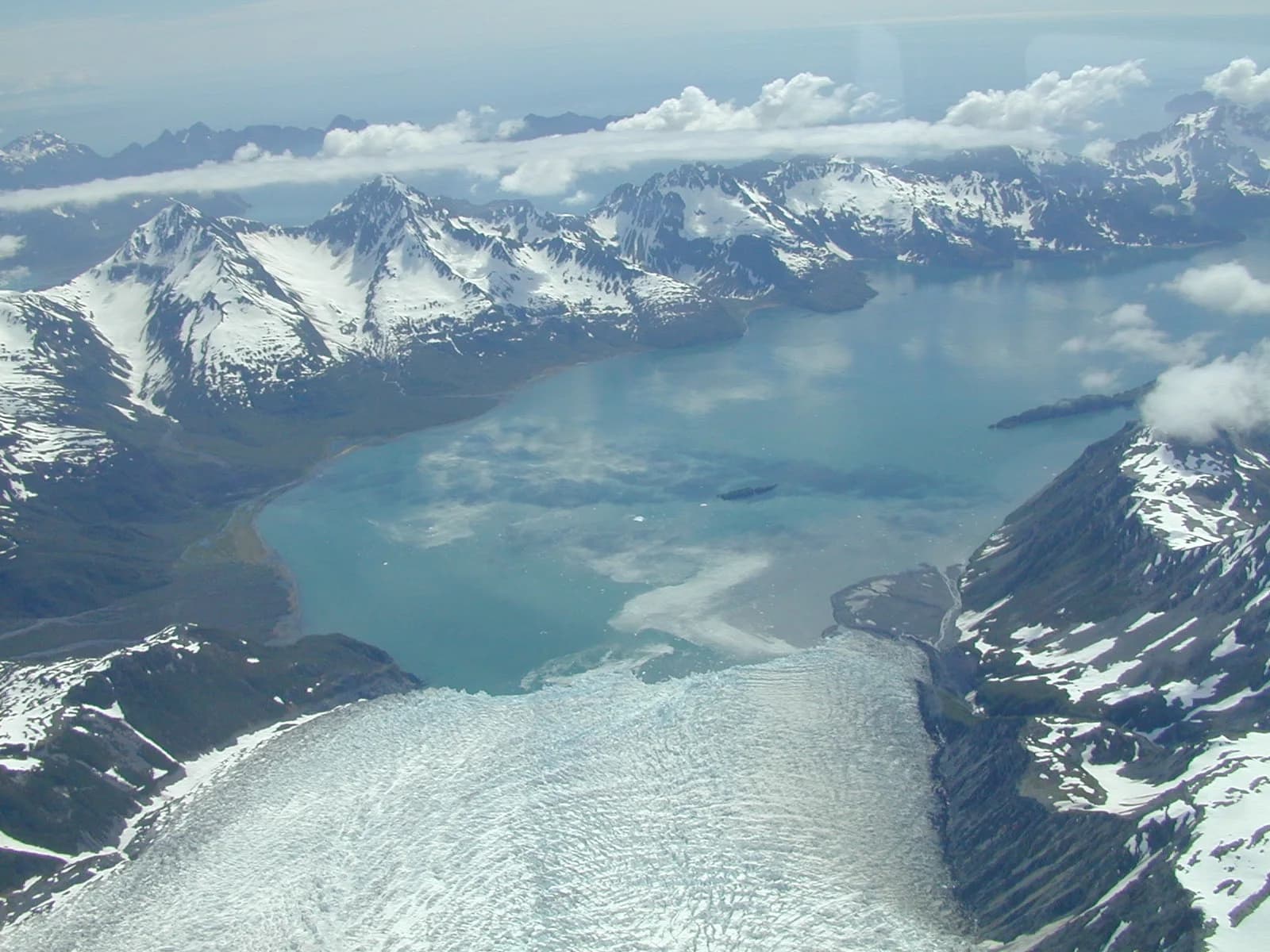 An aerial view of Aialik Glacier flowing from the Harding Icefield toward the water in Kenai Fjords